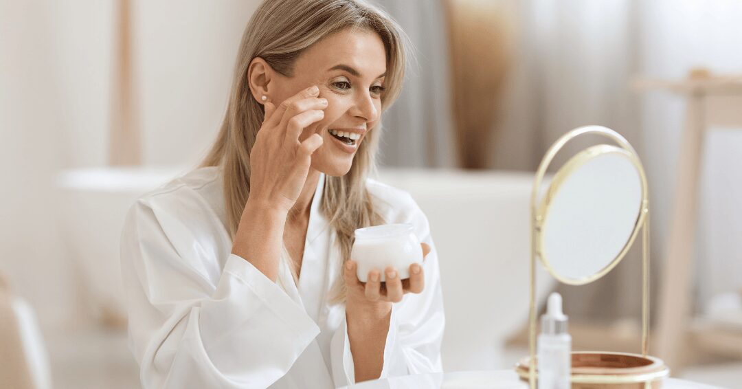 Chica mirándose en el espejo mientras se pone una crema de cara.