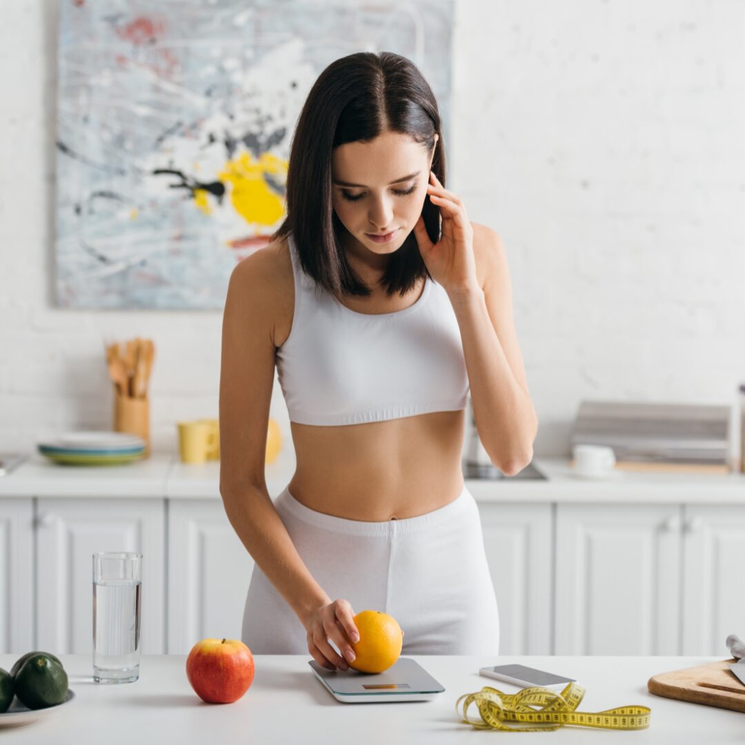 Chica en ela cocina pesando fruta