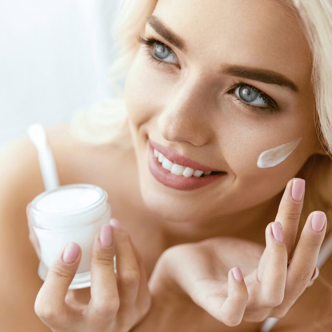 Chica con un tarro de crema y un poco de crema en la cara