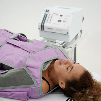 Chica estirada en una camilla con una máquina Zemits